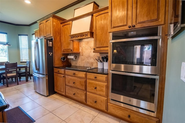 kitchen featuring decorative backsplash, ornamental molding, dark stone countertops, light tile patterned flooring, and stainless steel appliances