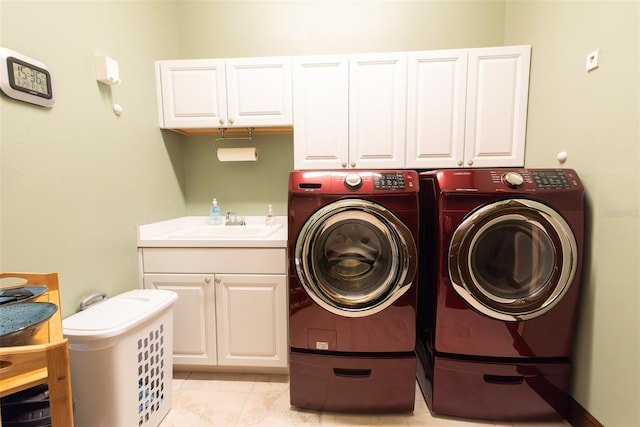 washroom with light tile patterned floors, sink, separate washer and dryer, and cabinets