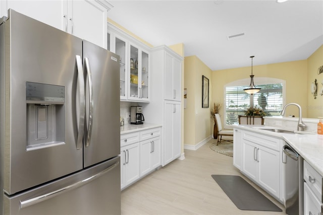 kitchen with sink, white cabinetry, light hardwood / wood-style floors, stainless steel appliances, and light stone counters