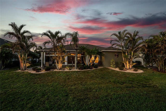 back house at dusk with a lawn