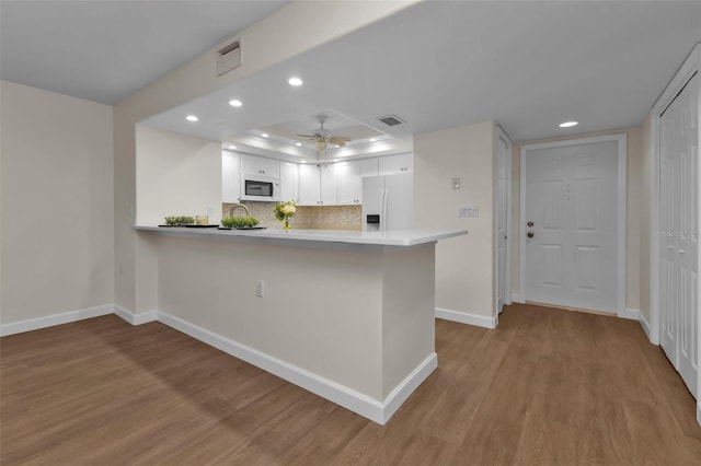 kitchen with kitchen peninsula, white cabinets, light wood-type flooring, and white appliances