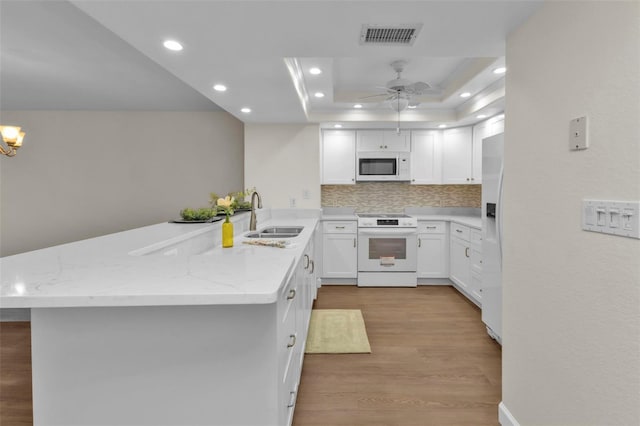 kitchen featuring kitchen peninsula, sink, white cabinetry, white appliances, and tasteful backsplash