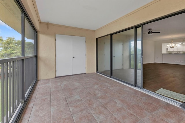 unfurnished sunroom featuring ceiling fan with notable chandelier