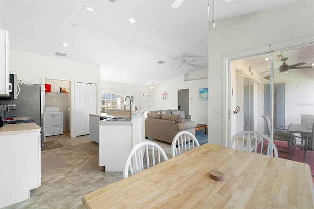 dining area with washer / clothes dryer, ceiling fan, sink, and vaulted ceiling