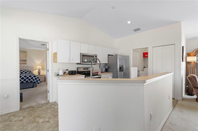 kitchen featuring lofted ceiling, white cabinets, stainless steel appliances, and light colored carpet