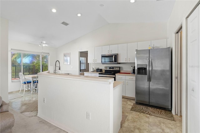 kitchen with lofted ceiling, white cabinetry, stainless steel appliances, and ceiling fan