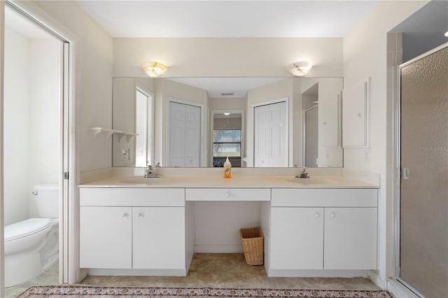 bathroom with vanity, a shower with shower door, and toilet