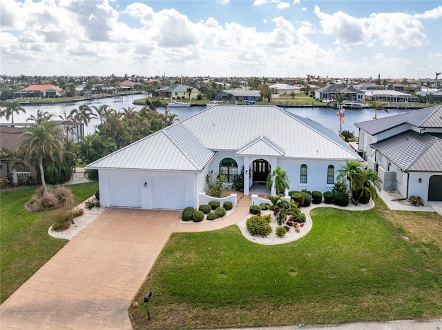 view of front of home with a garage, a water view, and a front lawn