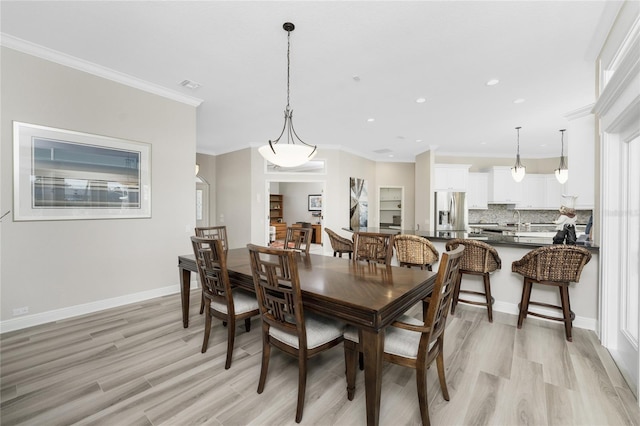 dining room featuring light hardwood / wood-style flooring, sink, and crown molding