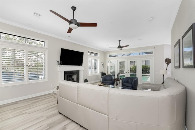 living room with french doors, light hardwood / wood-style floors, ceiling fan, and crown molding