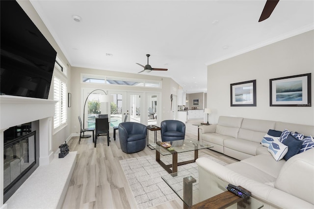 living room featuring ornamental molding, french doors, light hardwood / wood-style flooring, and ceiling fan