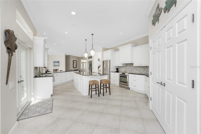 kitchen featuring stainless steel appliances, white cabinetry, a kitchen breakfast bar, a center island, and pendant lighting