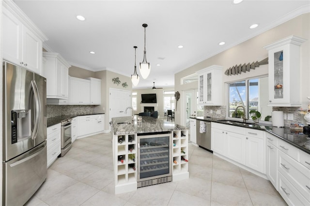 kitchen featuring sink, wine cooler, appliances with stainless steel finishes, a kitchen island with sink, and pendant lighting