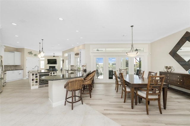 dining space featuring wine cooler, sink, french doors, and ornamental molding