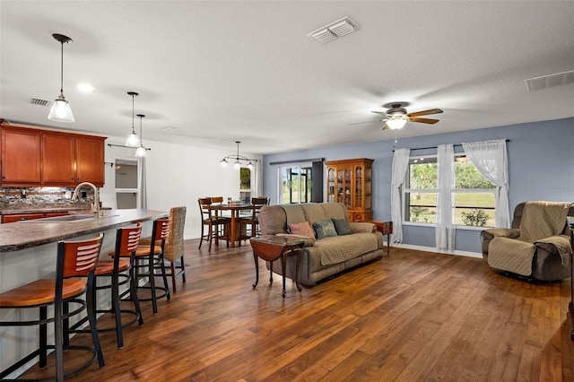 living room featuring a textured ceiling, sink, dark hardwood / wood-style floors, and ceiling fan with notable chandelier