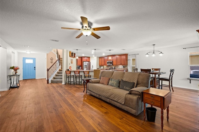 living room with ceiling fan, a textured ceiling, and light hardwood / wood-style flooring