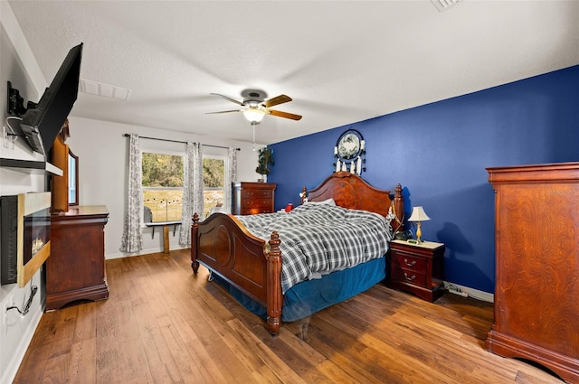 bedroom featuring hardwood / wood-style flooring, ceiling fan, and a textured ceiling