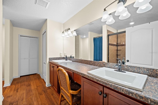 bathroom with hardwood / wood-style flooring, vanity, a textured ceiling, and walk in shower