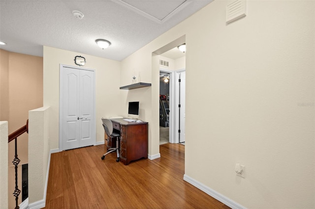 interior space with white cabinets, a breakfast bar, a textured ceiling, and light hardwood / wood-style flooring