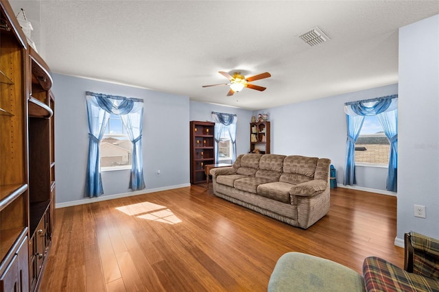 living room featuring a textured ceiling, hardwood / wood-style floors, a wealth of natural light, and ceiling fan