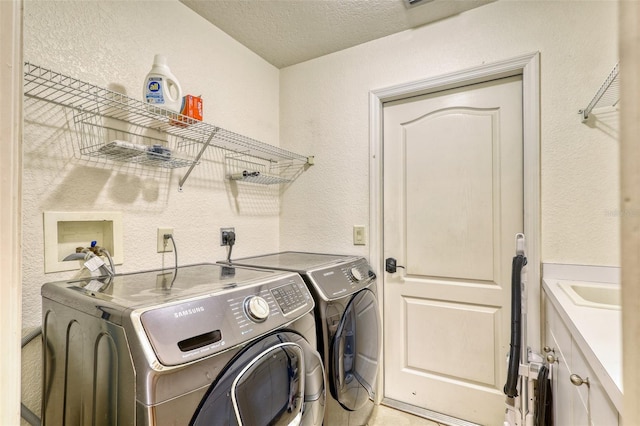 laundry room featuring cabinets, independent washer and dryer, a textured ceiling, and sink