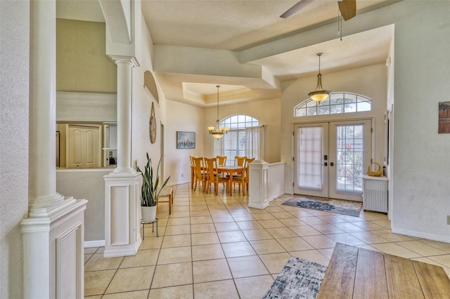 tiled foyer with french doors, ceiling fan with notable chandelier, a textured ceiling, and ornate columns