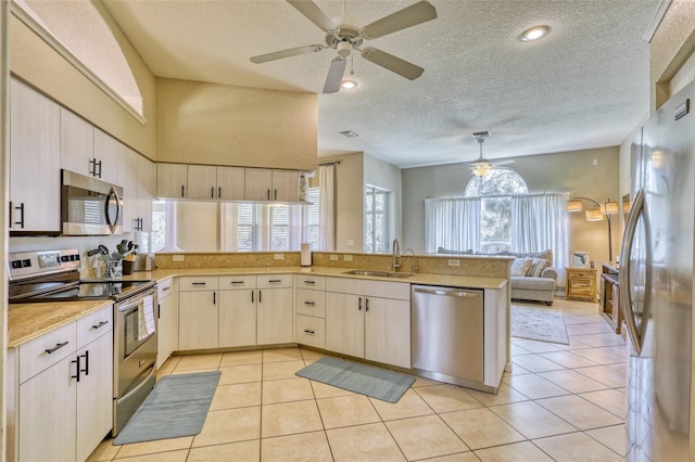 kitchen featuring kitchen peninsula, a textured ceiling, stainless steel appliances, sink, and light tile patterned flooring