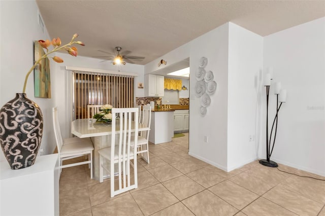 dining room featuring a textured ceiling, light tile patterned floors, and ceiling fan