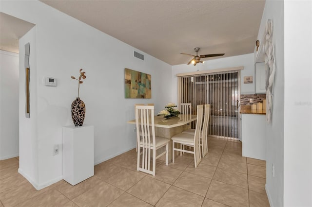 tiled dining space with a textured ceiling and ceiling fan