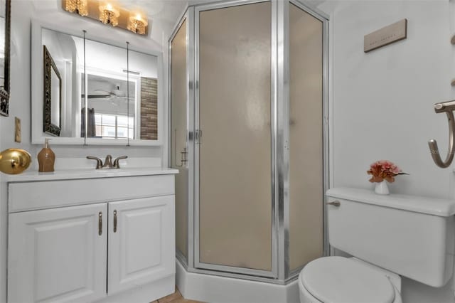 bathroom featuring vanity, toilet, walk in shower, and ceiling fan