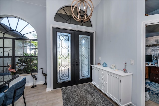 entrance foyer featuring light hardwood / wood-style flooring, french doors, and a chandelier