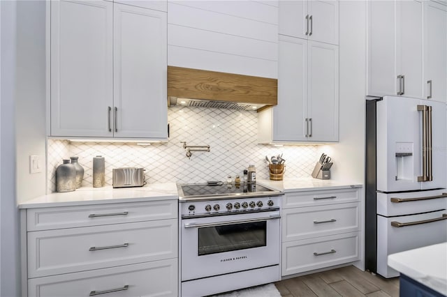 kitchen featuring white cabinets, high quality fridge, backsplash, and electric range oven