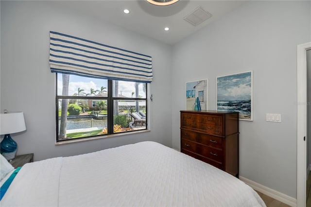 bedroom featuring a water view and hardwood / wood-style flooring