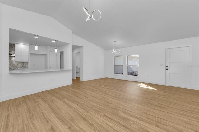 unfurnished living room with light wood-type flooring, lofted ceiling, and a notable chandelier