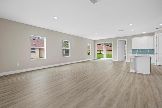 unfurnished living room featuring sink and light wood-type flooring