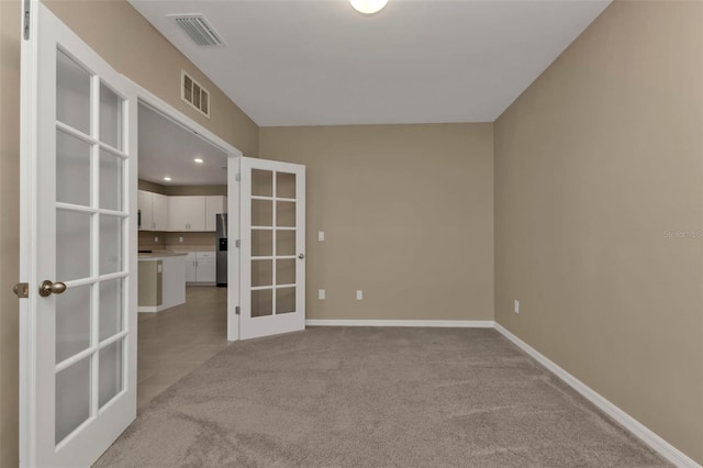 empty room with french doors and light colored carpet