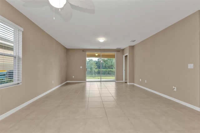 tiled empty room featuring a wealth of natural light and ceiling fan