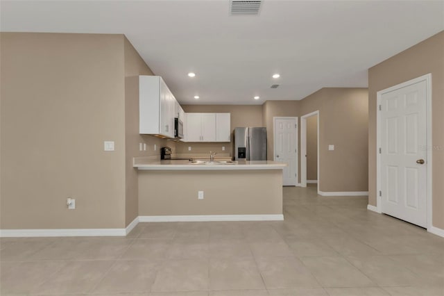 kitchen with kitchen peninsula, appliances with stainless steel finishes, light tile patterned flooring, and white cabinets