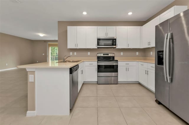 kitchen featuring kitchen peninsula, sink, light tile patterned floors, white cabinetry, and appliances with stainless steel finishes