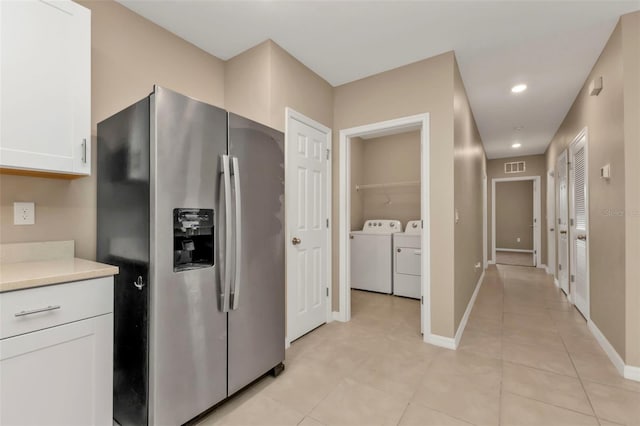 kitchen featuring white cabinets, light tile patterned flooring, independent washer and dryer, and stainless steel fridge with ice dispenser