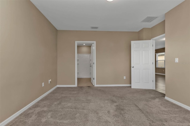 unfurnished bedroom featuring light colored carpet and ensuite bath