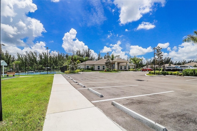 view of car parking with a yard and tennis court