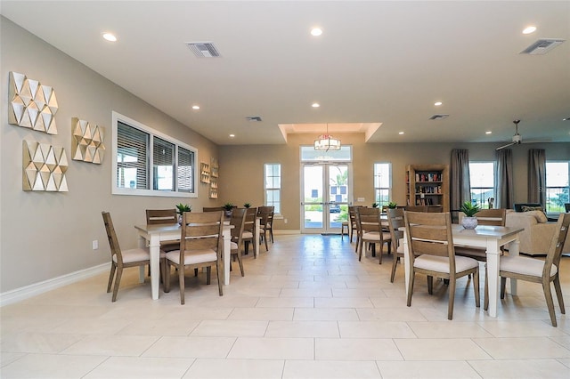 tiled dining space featuring a chandelier and french doors