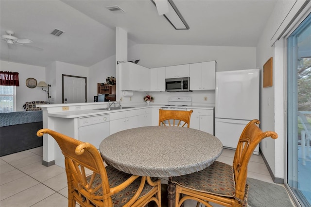 kitchen with lofted ceiling, kitchen peninsula, light tile patterned floors, white cabinets, and white appliances