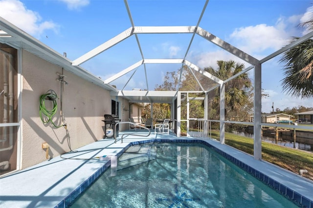 view of pool with grilling area, a patio area, and glass enclosure