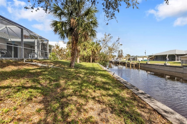 exterior space featuring a water view, glass enclosure, and a lawn