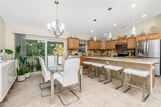 kitchen featuring appliances with stainless steel finishes, tasteful backsplash, a kitchen island with sink, a notable chandelier, and hanging light fixtures