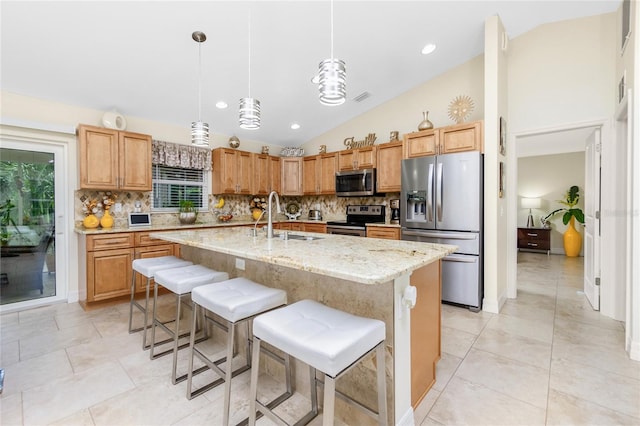 kitchen featuring sink, hanging light fixtures, an island with sink, vaulted ceiling, and appliances with stainless steel finishes