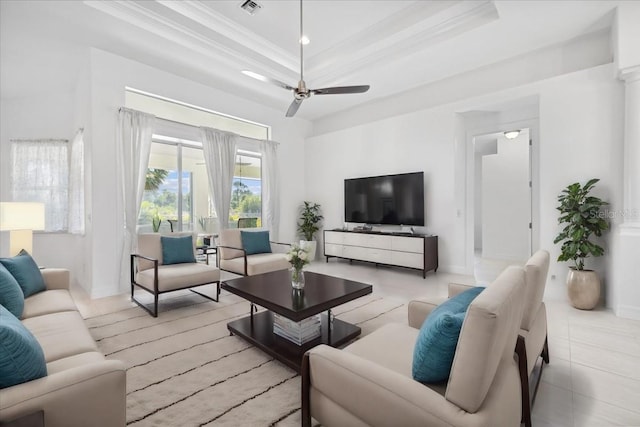 living room featuring baseboards, ornamental molding, ceiling fan, and a tray ceiling