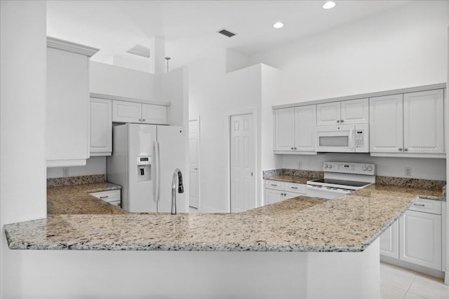 kitchen with visible vents, white appliances, recessed lighting, light stone counters, and a sink
